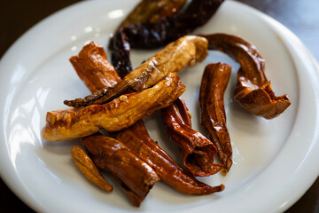 Fried colorful chili peppers, a traditional appetizer or side dish from turkish cuisine, close up on a white plate, offering spicy and hot taste
