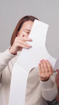 white seamstress approving pattern prototype while sample fitter watches, hold large paper piece, align curves and evaluate balance, exchange feedback and refine edges, warm collaborative mood