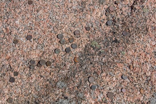 Close-up of Aljava Ukukivi (Offering stone of Uku) boulder with offering coins left on rock in sunny summer weather, Muhu, Estonia.