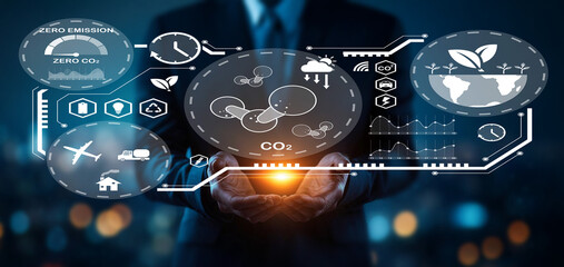 Businessman holding glowing sphere with environmental icons and data visualizations representing eco-friendly technology and zero emissions concept