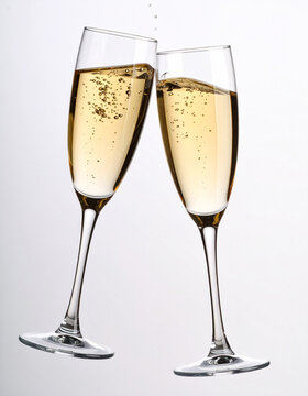 Dos copas de champ&aacute;n color dorado brindando en brindis de fin de a&ntilde;o o celebraci&oacute;n de fiesta o aniversario en fondo blanco liso  