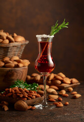 Italian liqueur Amaretto with almonds nuts on a brown background.