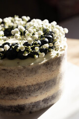 Homemade cake decorated with fresh flowers on wooden table