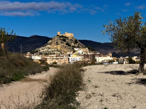 Medieval castle surrounded by long fortified wall on top of a hill with the town below