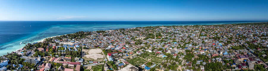 panoramic aerial view across northwest part of Nungwi, a large village located in the far northern end of island of Zanzibar, with Nungwi Beach and Indian Ocean in the background 