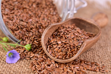 Flax seeds and flowers poured out of a glass jar. Superfood. Close-up.
