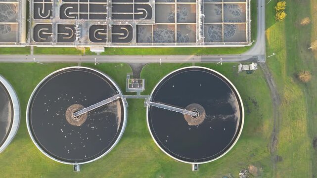 Aerial view of water treatment facility showcasing circular tanks and machinery. Sewerage system surrounded by greenery. Modern industrial plant of big city. Ecology friendly factory