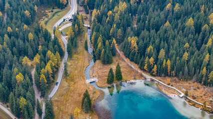 aerial landscape view of area around south part of turquoise Antholzer See, a lake in the Antholzertal in South Tyrol, Italy, with with outflow,, surrounding autumn forest and "Obertaler St"