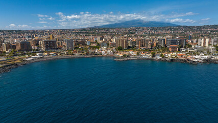 Obraz premium Aerial view of San Giovanni li Cuti beach. It is a small seaside village in the eastern part of the city of Catania, Sicily, Italy. In the background, on the horizon, is Mount Etna in silhouette.
