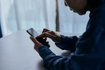 部屋でスマホを操作するシニア女性