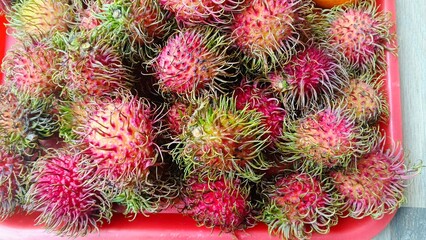 Fresh Red Rambutan Fruit Pile in Tray.