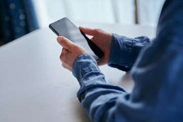 部屋でスマホを操作するシニア女性