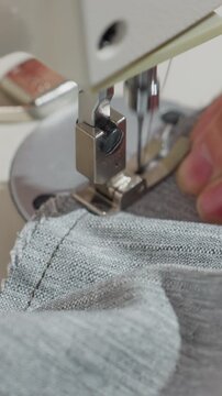 closeup fabric seam under presser foot, technician guiding jersey cloth with steady hands, precise feed and tension adjustments, seam finishing for apparel production, metallic throat plate