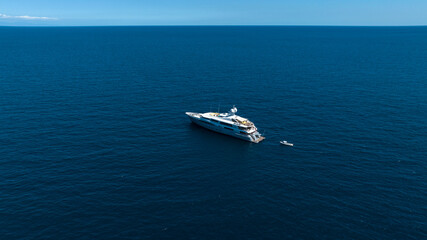 Aerial view of a yacht anchored in the middle of the sea. The ocean waters stretch to the horizon on this beautiful sunny day. © Stefano Tammaro
