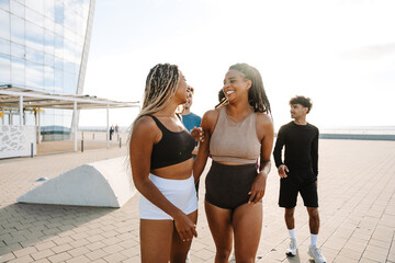 Two female athletes laugh as a group of three athletes follow them