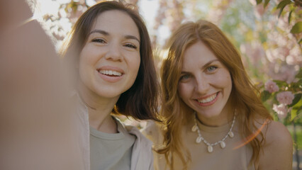 Two friends smile and enjoy a day in a flower garden during springtime, surrounded by blooming...