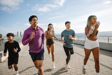 Obraz premium Group of four athletes laughing while running next to female athlete