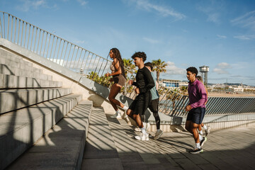 Fototapeta premium A group of three athletes run up the stairs while a male athlete is behind them