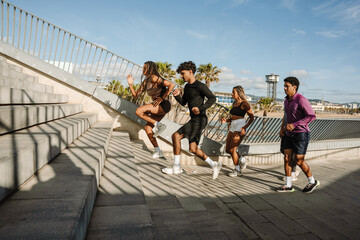A female and male athlete run up the stairs while other male and female athletes are behind them