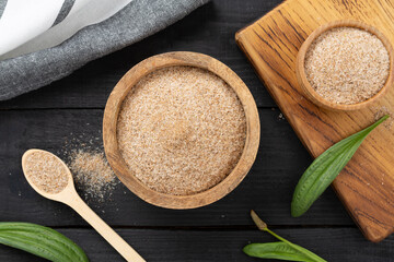 Psyllium husk powder with fresh leaves on wooden background, top view © Liami
