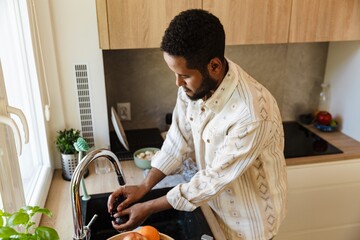 Father stands at the sink and washes food in it