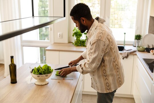 Father holding a knife and salad while standing at the table