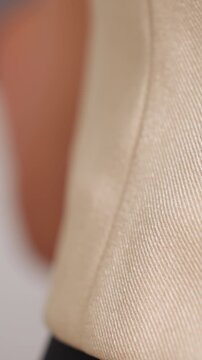 white inspector feeling beige fabric texture and hem, caucasian woman runs fingers over woven weave and seam, studio closeups of weave and finish, tactile quality control and satisfied finishing