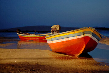 Colorful red and yellow fisherman boats landed on Jericoacoara beach at evenning