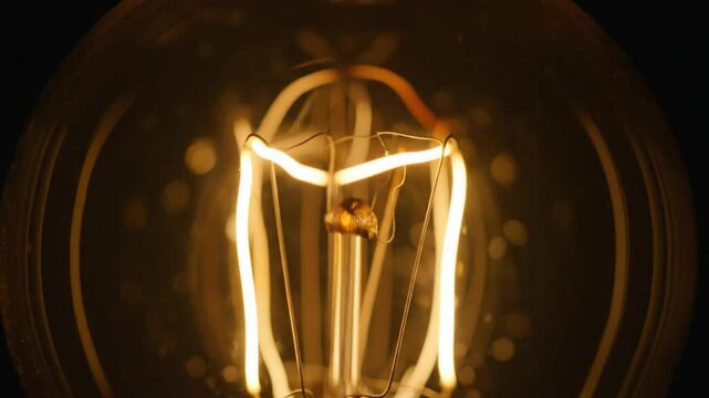 Close-up of a glowing incandescent light bulb filament with buzzing sound effects for vintage ambiance