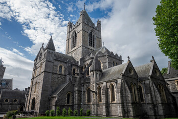 Christ Church Cathedral in Dublin with its Gothic architecture, arched windows, and central tower, set against a partly cloudy sky with a grassy area
