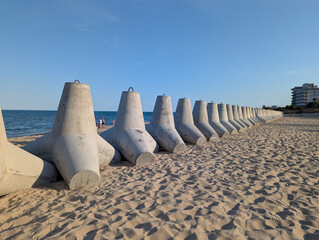 Weathered tetrapod blocks guard the sandy beach.