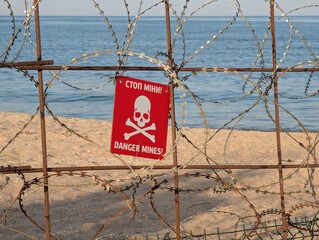 Chernomorsk, Ukraine, July 27, 2025: A mine danger sign stands on the sandy seashore.