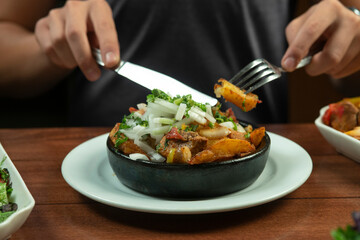 Man eating Beef stew with potatoes, carrots and herbs on black background with copy