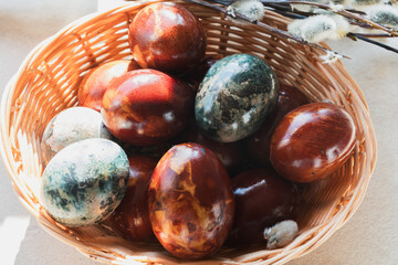 Close-up of wicker basket with naturally dyed Easter eggs and willow branches