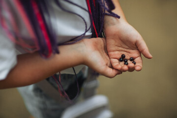 A currant in the hands of a girl with dreadlocks