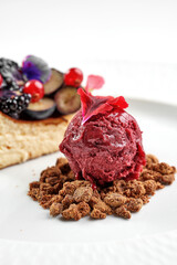 dessert featuring a slice of cheesecake topped with fresh mixed berries and edible flowers, served alongside a scoop of berry sorbet