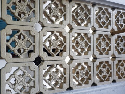 Close-up of a traditional decorative ceramic or terracotta vent screen rosteror jalusi with an interlocking floral pattern, providing airflow and light in Southeast Asian architecture.