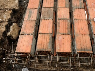 High-angle close-up of hollow clay blocks sometimes called slabs set horizontally on a rebar framework, showing the initial stages of a floor or beam construction.