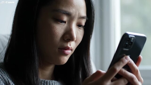 Serious Young Asian Woman Using Smartphone at Home, Close-up