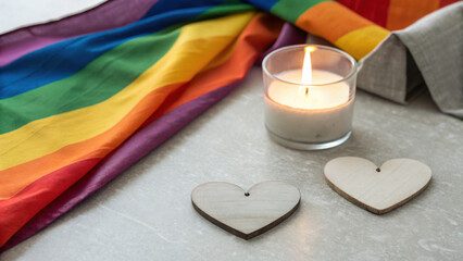 Lgbtq Romantic Theme. Elegant romantic setup with muted rainbow flag, wooden hearts, and lit candle creating warm atmosphere