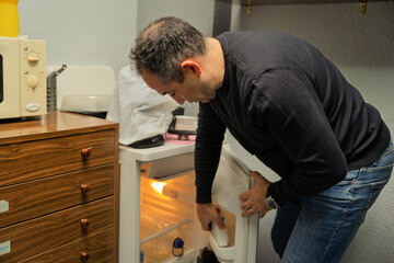 Man searching for food in an empty refrigerator
