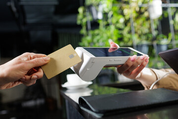 Obraz premium NFC contactless card payment at reception counter with handheld POS terminal