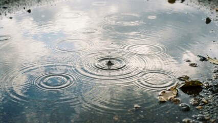 Raindrops Creating Ripples in a Reflective Puddle on a Cloudy Day