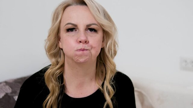 Mature woman doing facial exercises inflating cheeks and moving air side to side to reduce wrinkles and maintain youthful healthy skin appearance