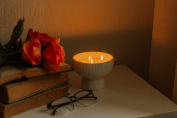 Warm candlelight with soft rose accents and vintage books creating a calm, intimate ambience....
