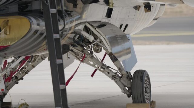 Detailed view of aircraft nose landing gear assembly including strut wheel tire shock absorber and retraction components in down position