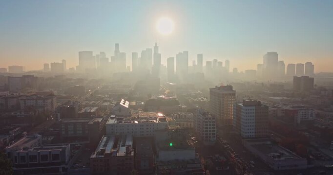 Stunning aerial silhouette shot at Sunrise over Downtown Los Angeles emerge from fog with golden morning light