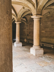 Fototapeta premium An arched gallery with massive stone columns. A bright stone space with symmetrical vaults, soft natural light, and textured stonework.
