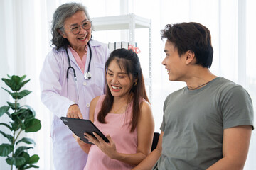 Senior female obstetrician consulting pregnant woman and her husband in medical clinic or hospital planning pregnancy. Visit to hospital, planning pregnancy, happy patients, trust and respect concept