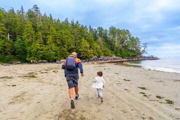 Father and son running on a sandy beach in tofino, vancouver island © unai